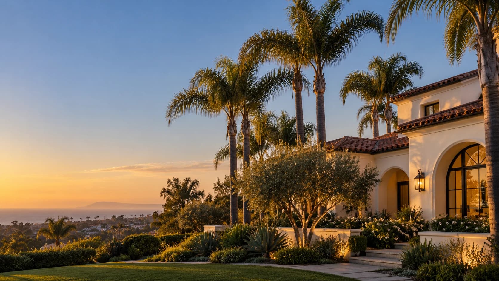 A Mediterranean-style home with palm trees and landscaped gardens at sunset