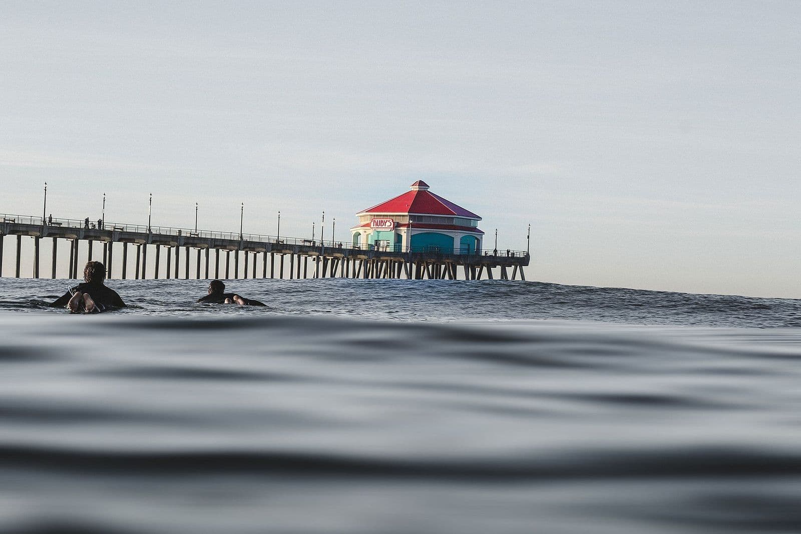Swimmers in the ocean beside the Huntington Beach pier