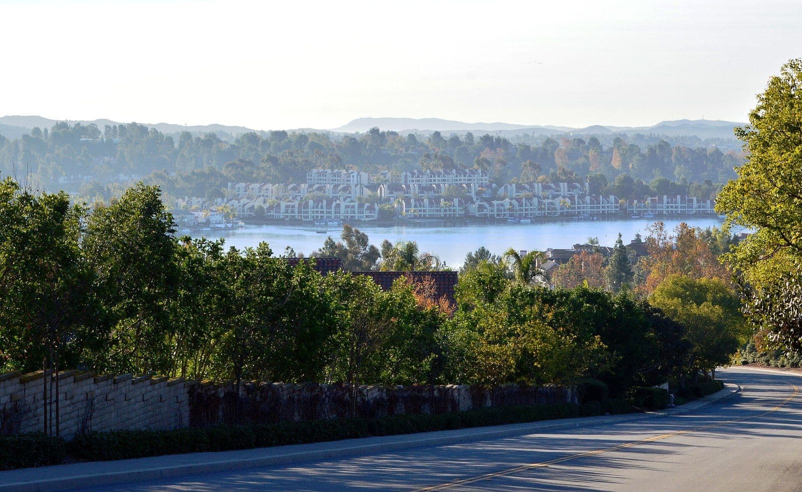 Lake Mission Viejo seen through trees from a hillside street